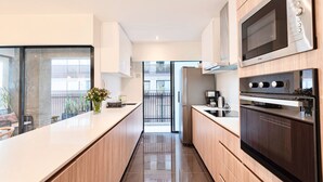 A modern kitchen with wooden cabinets, a large island, and stainless steel appliances. - ✶ Maras Residence ✶ LUXURY Rooftop Pool & Grill (Miraflores)