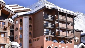 Un hôtel à plusieurs étages, doté de balcons et offrant une vue sur les montagnes.