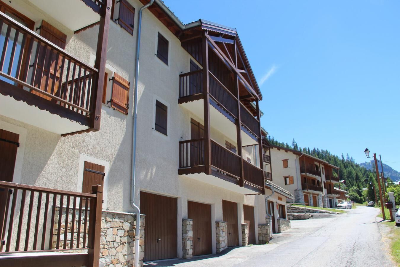A row of multi-story buildings with balconies, stone foundations, and a clear sky.