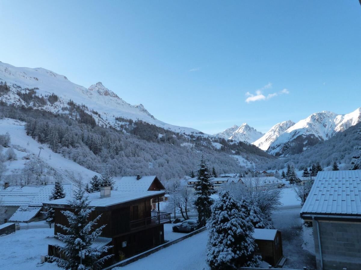Ein verschneites Bergdorf mit Holzhäusern und blauem Himmel.