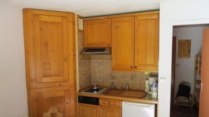 A compact kitchen with wooden cabinets, a dishwasher, a sink, and a stove. - 350m from ski slopes, balcony, parking, tv, ski locker, 24m², Valloire (Valloire)