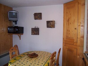 A dining area with a table set for four, a television mounted above it, and three small decorative items on the wall. - 230m from resort center, balcony, parking, tv, ski locker, 24m², Valloire (Valloire)