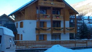 A wooden chalet with multiple balconies, a wooden fence, and a snow-covered ground. - 300m from ski slopes, 2nd floor, balcony, ski locker, 38m², Valloire (Valloire)