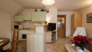 A compact kitchen with a dining area, a television, and a wooden cabinet. - 300m from ski slopes, 2nd floor, balcony, ski locker, 38m², Valloire (Valloire)