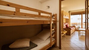 A bunk bed with a wooden frame and a mattress with a pillow. There is a chair and a small table in the room. - 300m from ski slopes, 2nd floor, balcony, ski locker, 38m², Valloire (Valloire)
