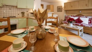 A dining area with a wooden table set for four, surrounded by light-colored cabinets and a tiled backsplash. - 300m from ski slopes, 2nd floor, balcony, ski locker, 38m², Valloire (Valloire)