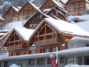 A row of wooden chalet-style buildings with balconies, covered in snow, indicating a winter setting. - 220m from ski slopes, floor -1, ski locker, 85m², Valloire (Valloire)