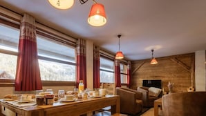 A cozy dining area with a wooden table set for breakfast, red curtains, and a television in the background. - 220m from ski slopes, floor -1, ski locker, 85m², Valloire (Valloire)