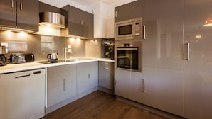 A modern kitchen with stainless steel appliances, grey cabinetry, and a wooden floor. - 220m from ski slopes, floor -1, ski locker, 85m², Valloire (Valloire)
