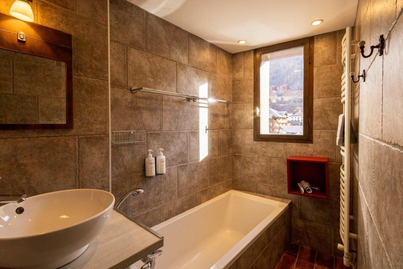 Une salle de bain moderne avec une grande baignoire, un lavabo et une fenêtre donnant sur un paysage enneigé.