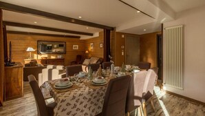 A dining area with a wooden interior, a television mounted on the wall, and a dining table set with plates and glasses. - 260m from ski slopes, 1st floor, terrace, balcony, tv, ski locker, 90m², Valloire (Valloire)