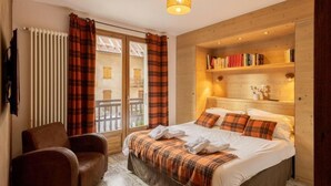 A bedroom with a bed, a chair, a bookshelf, and a window with curtains. - 260m from ski slopes, 1st floor, terrace, balcony, tv, ski locker, 90m², Valloire (Valloire)