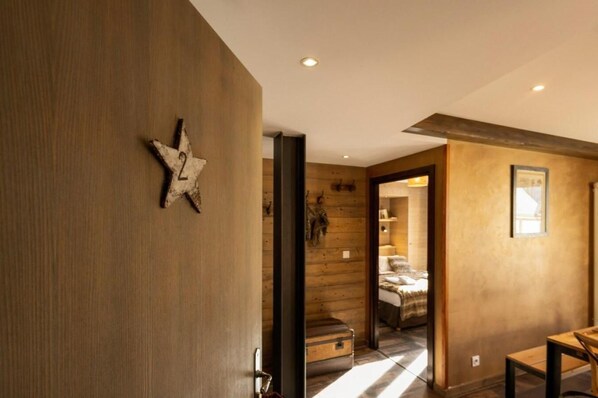 A hallway with a rustic wooden wall, a star decoration, and a suitcase on the floor.