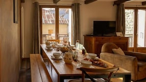 Un coin repas avec une table en bois mise pour le repas, un téléviseur et un canapé.