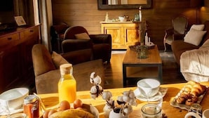 Un salon chaleureux avec un plancher en bois, un canapé, une table basse et une table à manger dressée avec de la nourriture et des boissons.