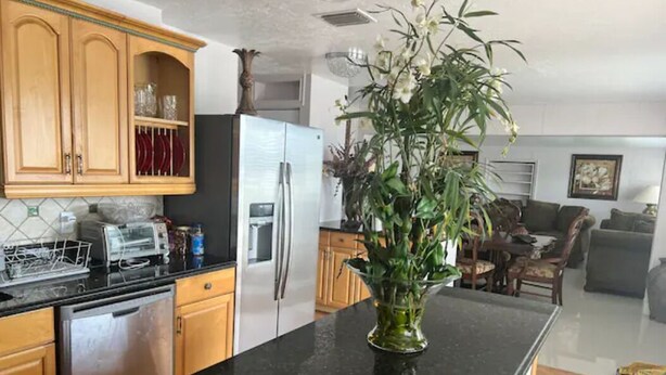 Eine Küche mit Holzausstattung, einem Kühlschrank, einem Geschirrspüler und einer großen Kochinsel mit Blumen in einer Vase.