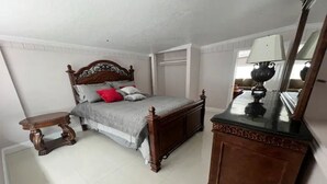 Ein Schlafzimmer mit einem hölzernen Bett, einem Nachttisch, einer Kommode und einem Spiegel.