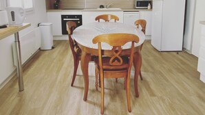 A compact kitchen with a round table, wooden chairs, a microwave, a refrigerator, and a dishwasher. - Isabelle's Country House (Germaine)