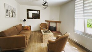 A modern living room with a brown sofa, a wooden coffee table, and a fireplace. - Isabelle's Country House (Germaine)