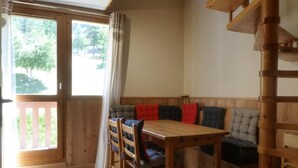 Ein Essbereich aus Holz mit Tisch und Stühlen, einer gepolsterten Bank mit Kissen und einer Holztreppe.