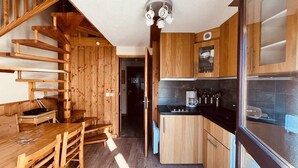 Eine kompakte Küche mit Holzausstattung, einer schwarzen Arbeitsplatte und einem eingebauten Herd.