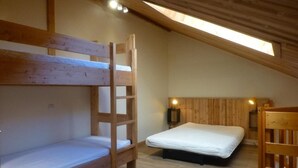 Ein Schlafraum mit Etagenbetten, einem Einzelbett, Holzwänden und einem Oberlicht.