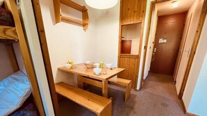 A compact room with a bunk bed, a small table with a bench, and a door leading to another room. - 250m from ski slopes, 3rd floor, balcony, tv, ski locker, 20m², Peisey-Vallandry (Landry)