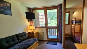 A compact room with a sofa, a small table, a TV, and a bunk bed. - 250m from ski slopes, 3rd floor, balcony, tv, ski locker, 20m², Peisey-Vallandry (Landry)