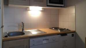 A compact kitchen with a sink, stove, and microwave.