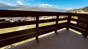 A balcony with a view of mountains and a village below.