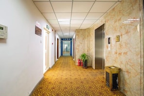 A hotel corridor with patterned carpet, doors, and a trash bin. - Binyue Hotel (East Building) (Hohhot)