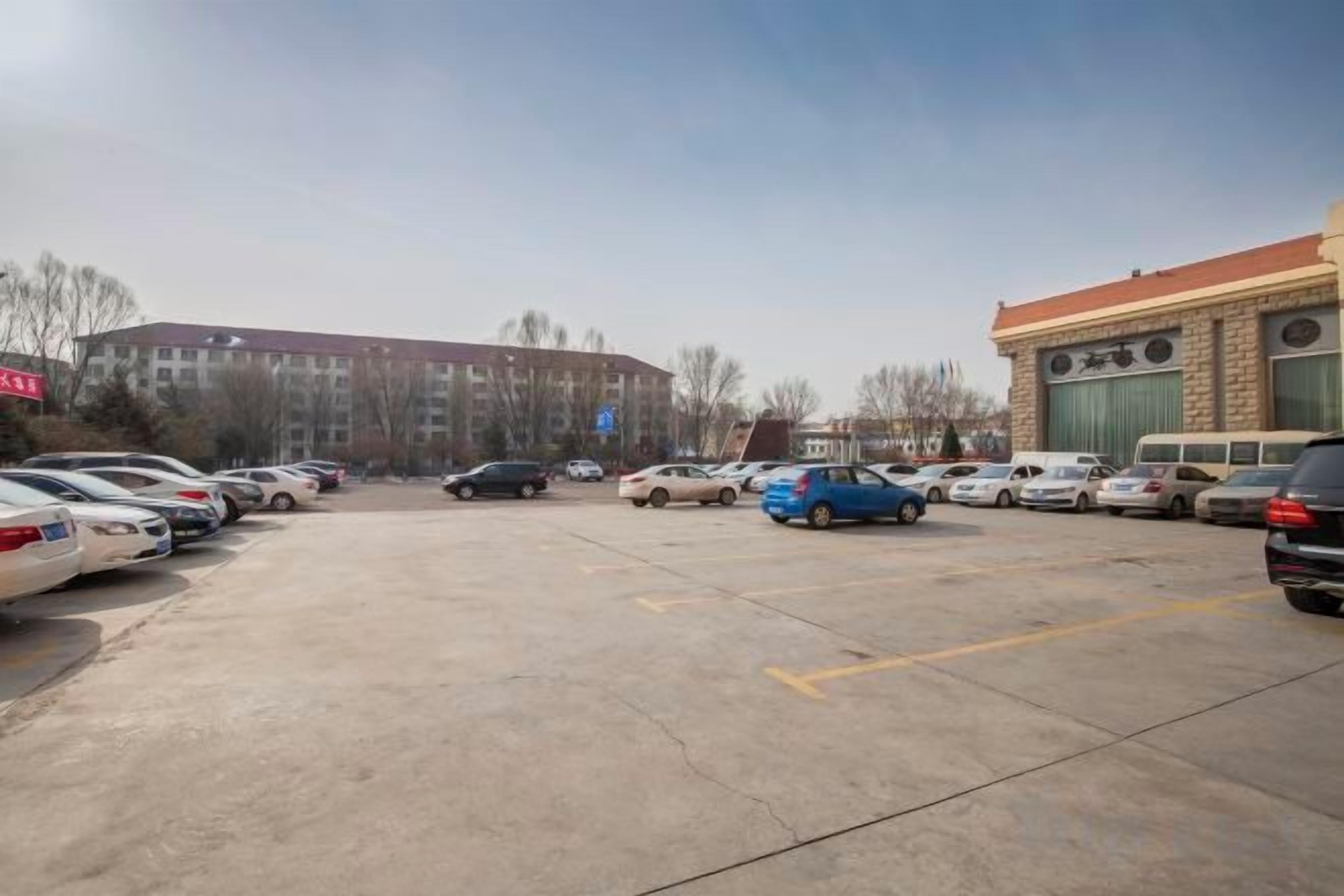 A parking lot with multiple cars and a building in the background.