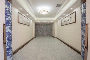 A hallway with a chandelier, framed calligraphy on the walls, and a patterned floor. - Binyue Hotel (East Building) (Hohhot)