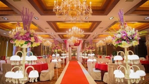 A banquet hall with a red carpet aisle, white chairs, and chandeliers. - Binyue Hotel (East Building) (Hohhot)