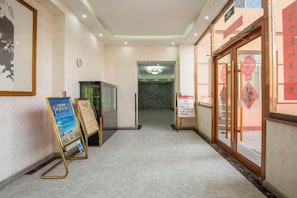 A hotel lobby with a reception desk, a clock, and informational signs. - Binyue Hotel (East Building) (Hohhot)