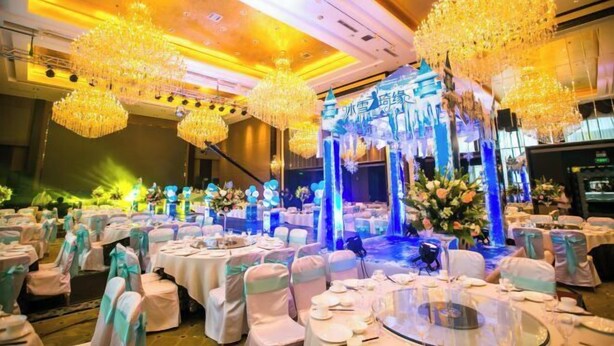 A banquet hall with round tables, white chairs, and chandeliers. - Binyue Hotel (East Building) (Hohhot)