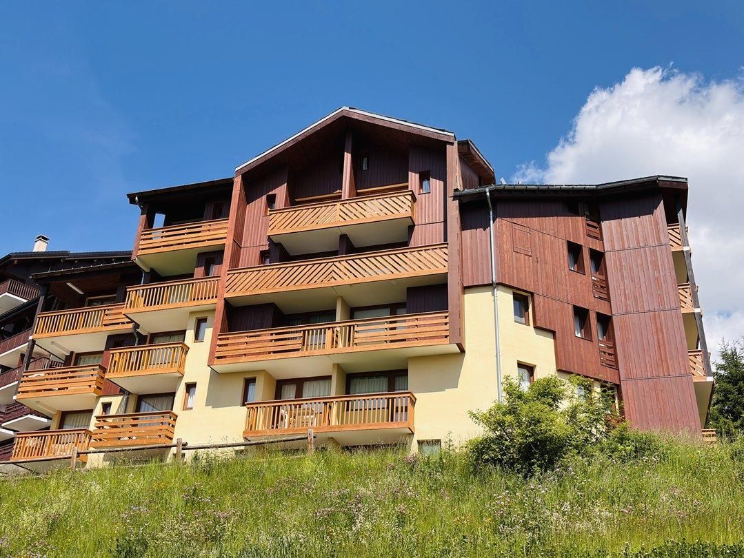 A multi-story building with balconies, likely a hotel or apartment complex, with a clear sky in the background.