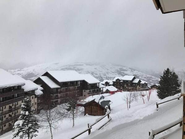 A snow-covered resort with multiple buildings, including a lodge and a hotel with balconies.
