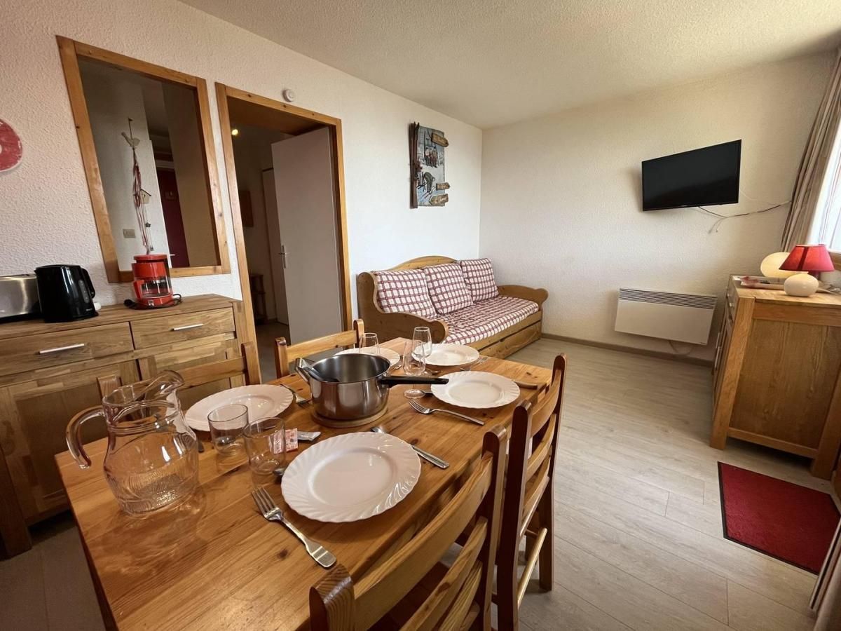 A dining area with a wooden table set for four, a coffee maker, and a television mounted on the wall.