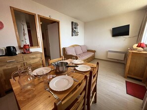 A dining area with a wooden table set for four, a coffee maker, and a television mounted on the wall. - 180m from ski slopes, 1st floor, balcony, tv, ski locker, 26m², Peisey-Vallandry (Landry)