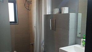Une petite salle de bain comprenant des toilettes, un lavabo, un espace douche et un miroir.