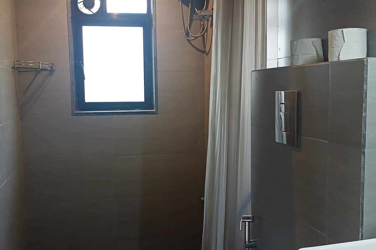 A small, compact bathroom with a window, a hand dryer, and a toilet.