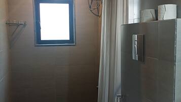 A small, compact bathroom with a window, a hand dryer, and a toilet.