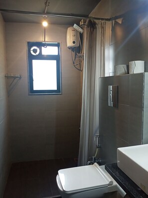 A small, compact bathroom with a window, a hand dryer, and a toilet. - Backpacker Cowies (Mumbai)
