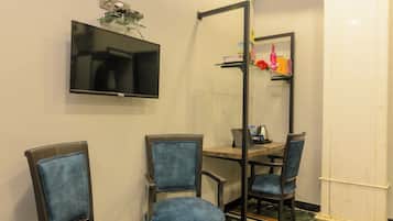 Baño con dos sillas, un espejo, un televisor y zona de ducha.