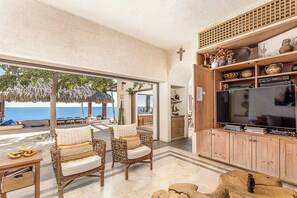 Relax in this spacious living area with a large TV, wicker furniture, and a stunning ocean view.
