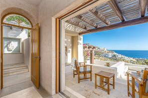 Relax on the balcony with a clear view of the coastal landscape, featuring a hillside with buildings and the sea.