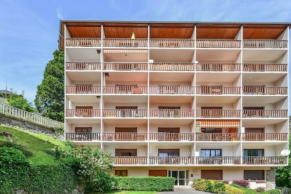 Un hotel de varios pisos con balcones, fachada de piedra y un jardín ajardinado.