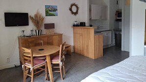 A compact living space with a dining area, kitchenette, and a bed.