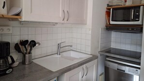 A kitchen with white cabinets, a stainless steel sink, a microwave, and a dishwasher.